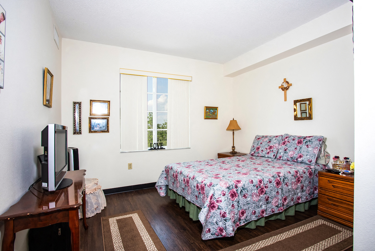 bedroom with large window, hardwood-style flooring, and model furnishings